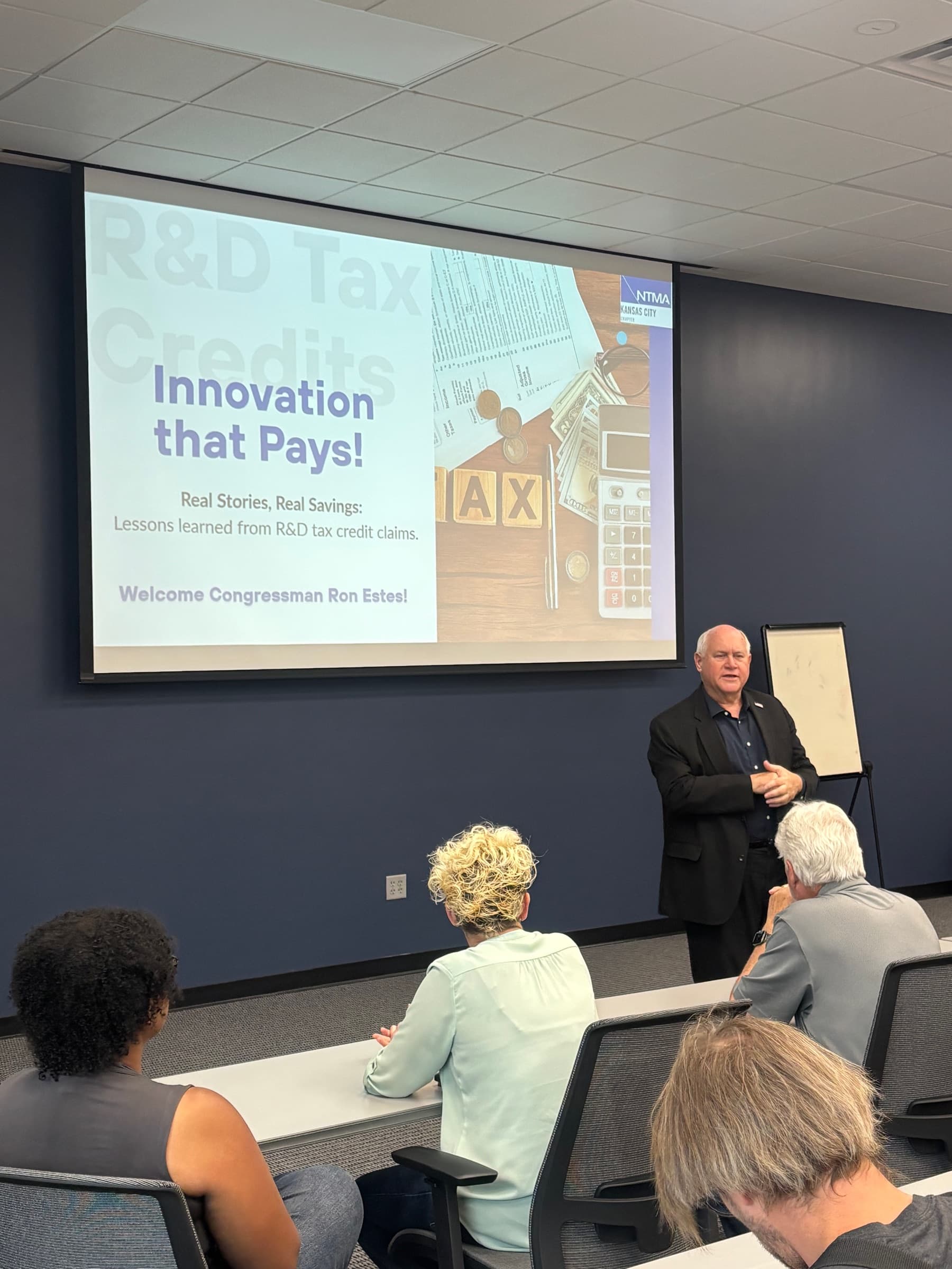Congressman Ron Estes speaking beside a slide titled Innovation that Pays about R&D tax credits