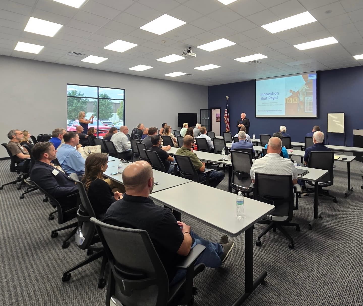 A full training room of members listening to Congressman Ron Estes at the front