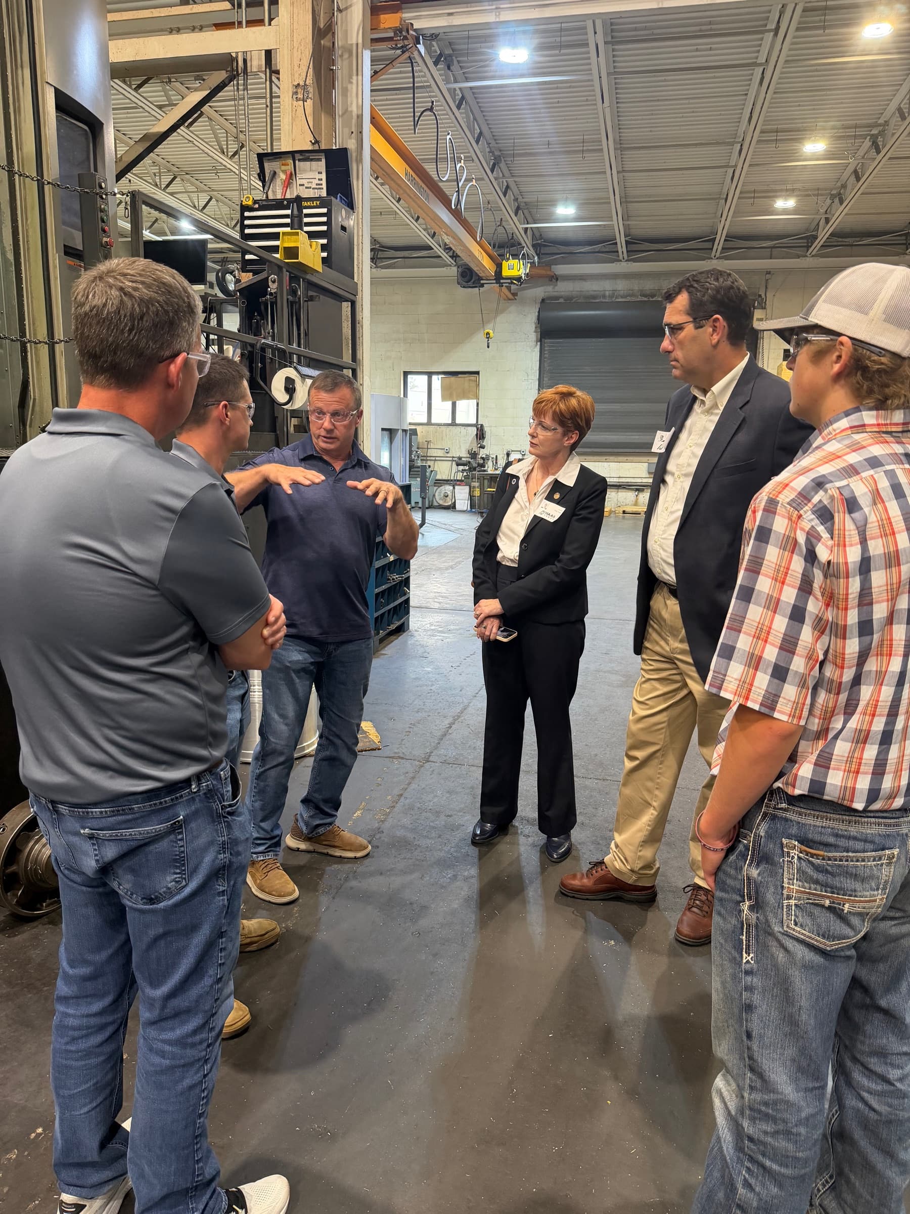 A shop owner explaining his operation to Congressman Derek Schmidt and chapter members on a plant floor