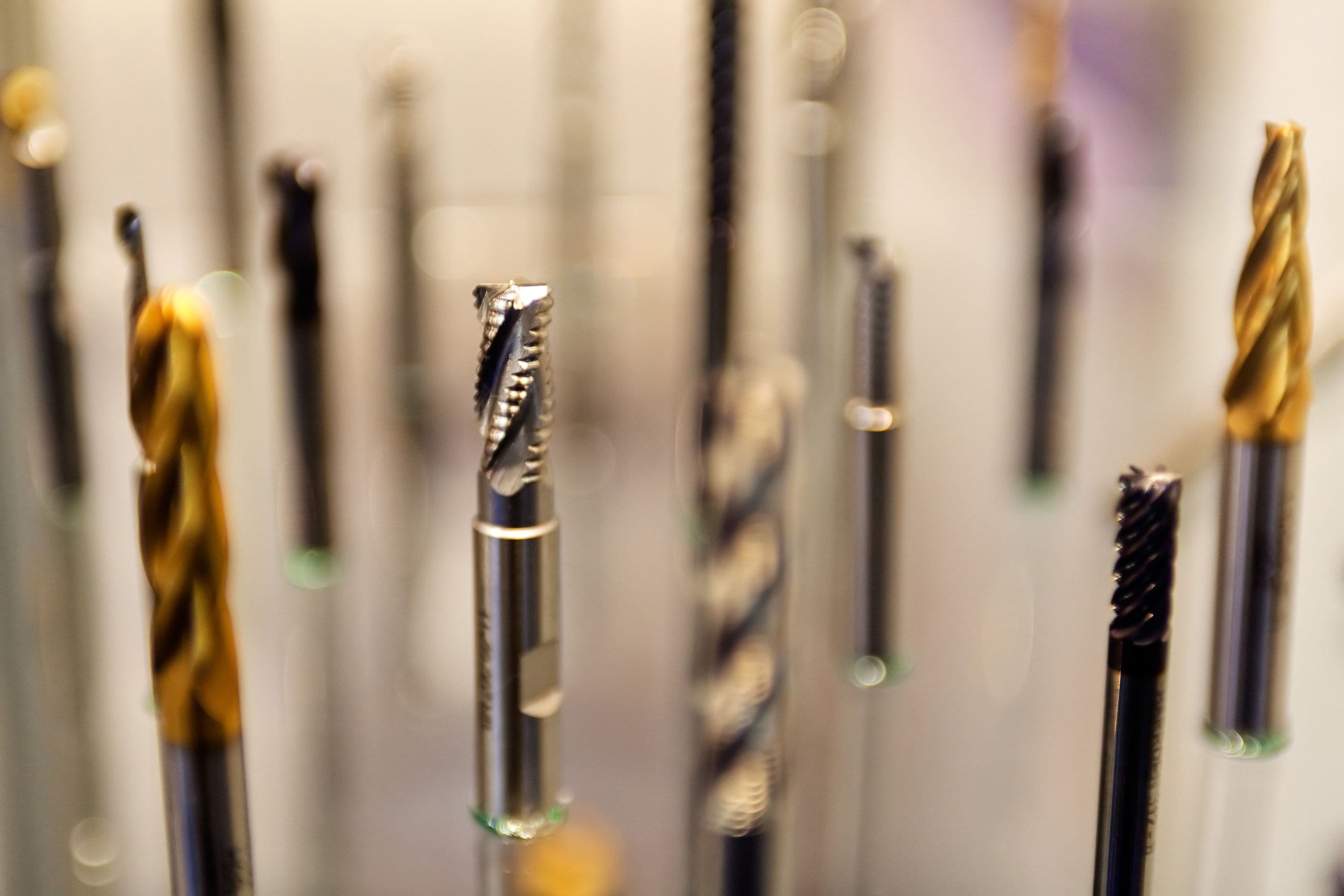 A row of end mills and drills standing upright, tips in focus