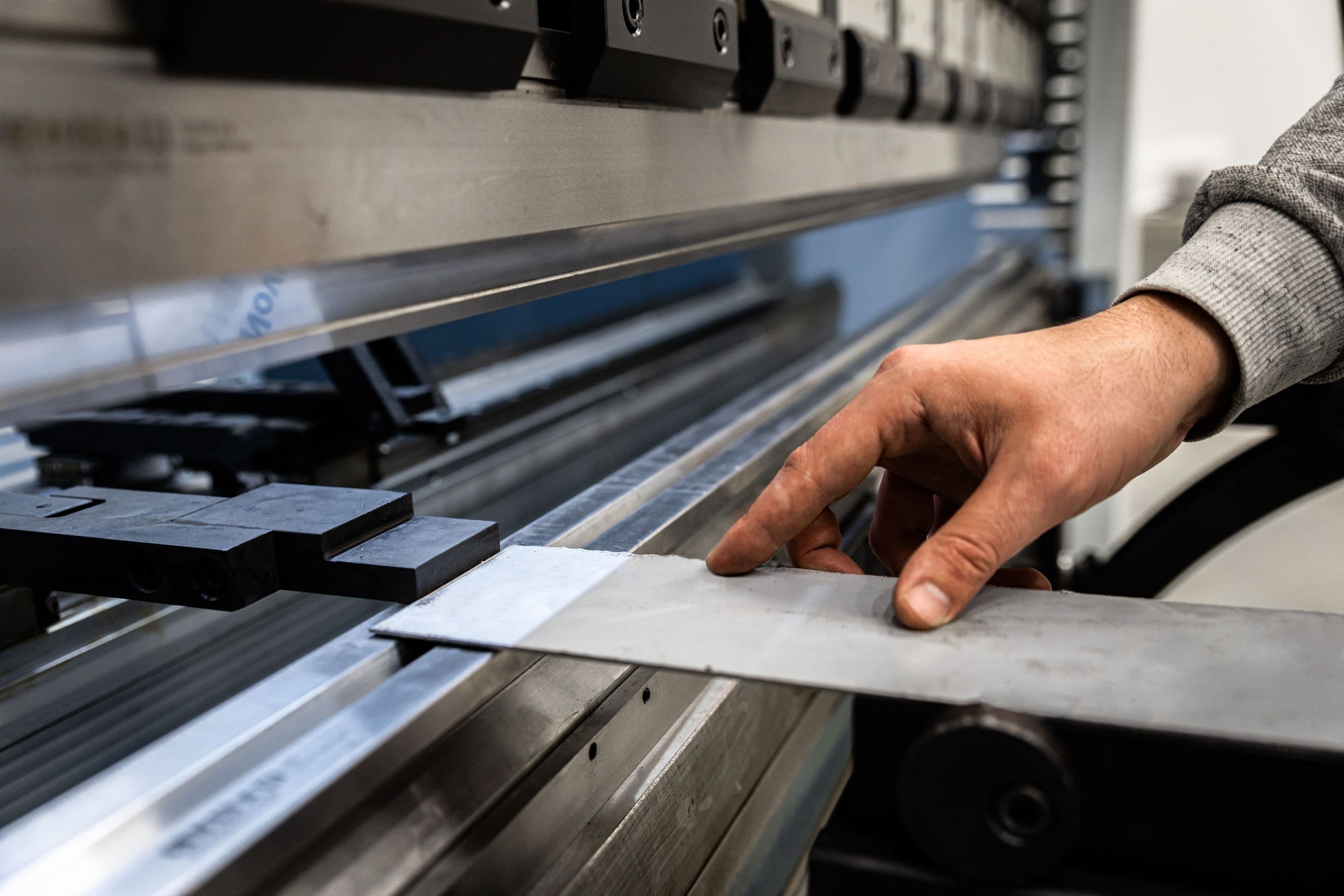 Hands feeding sheet metal into a press brake