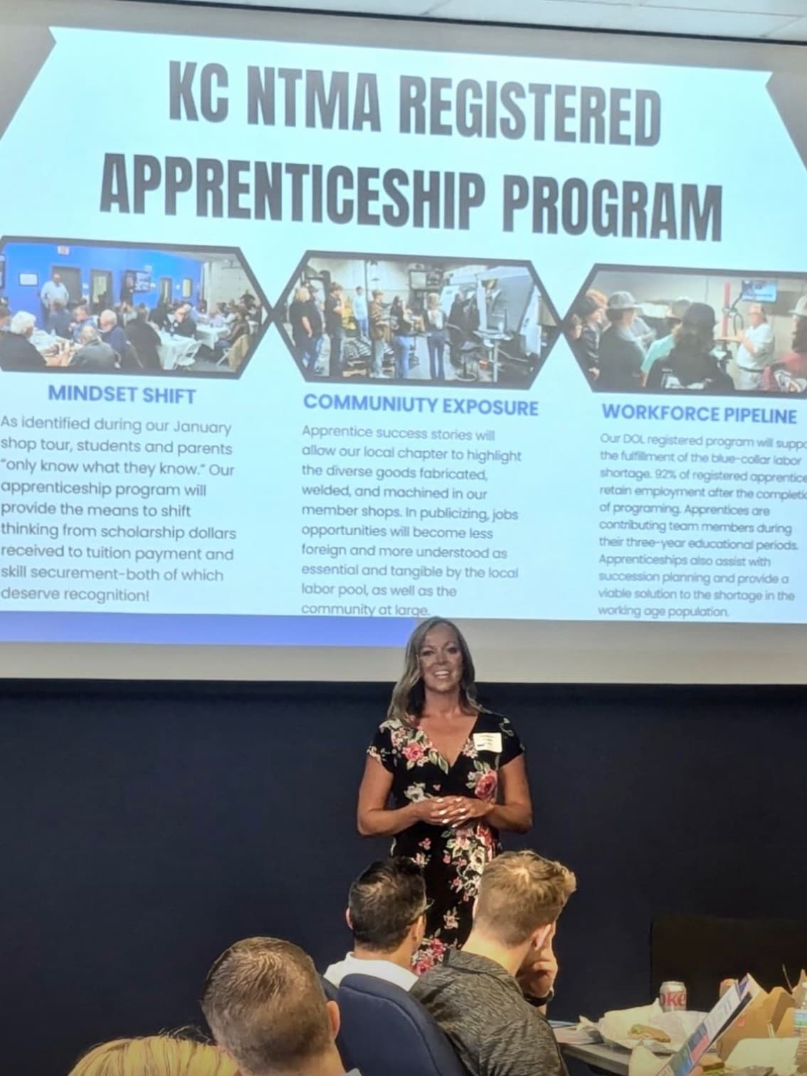 Katherine O'Toole presenting the KC NTMA Registered Apprenticeship Program to a room, the slide's three pillars above her