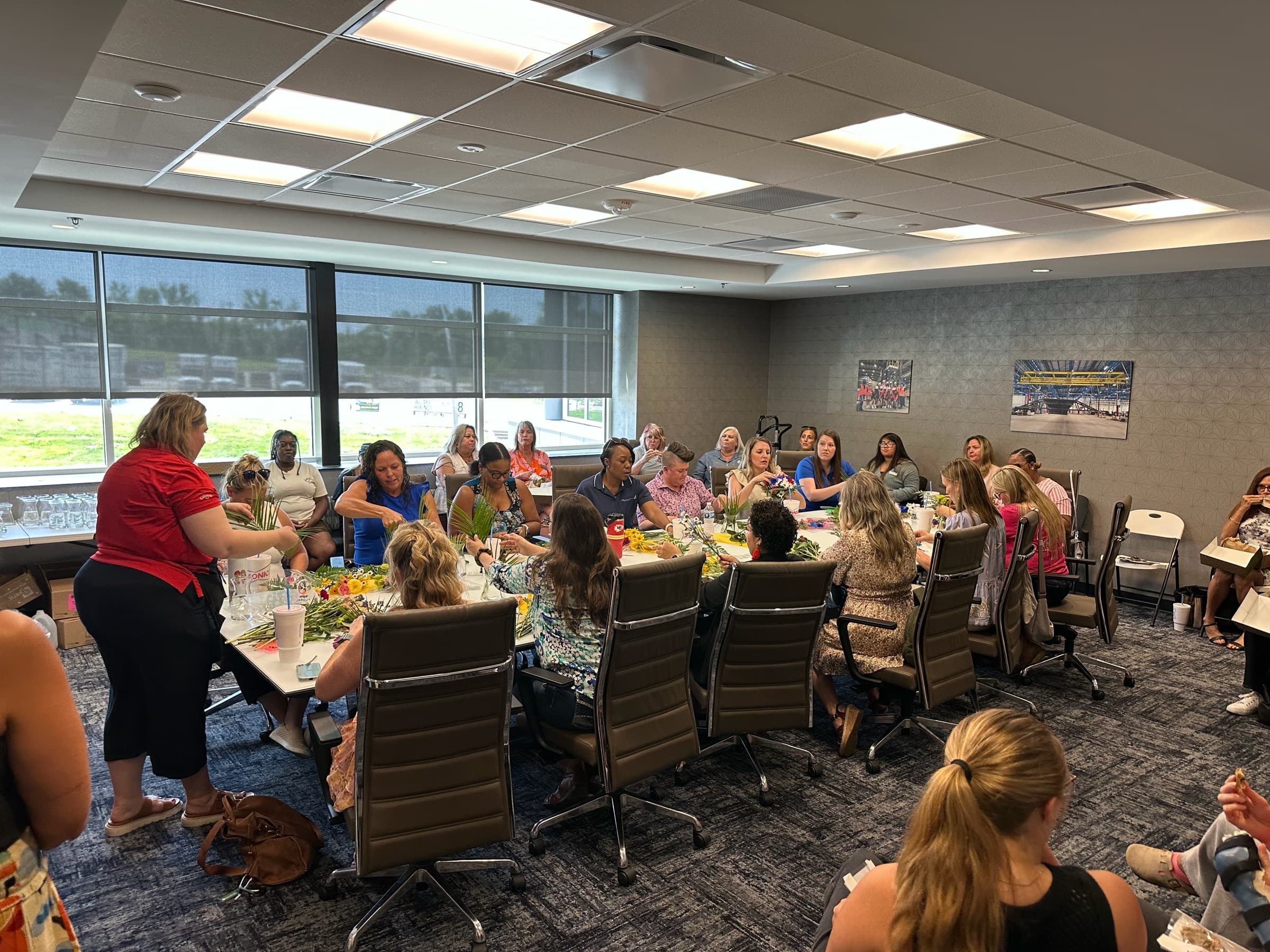 Members around a long table making flower arrangements in a conference room