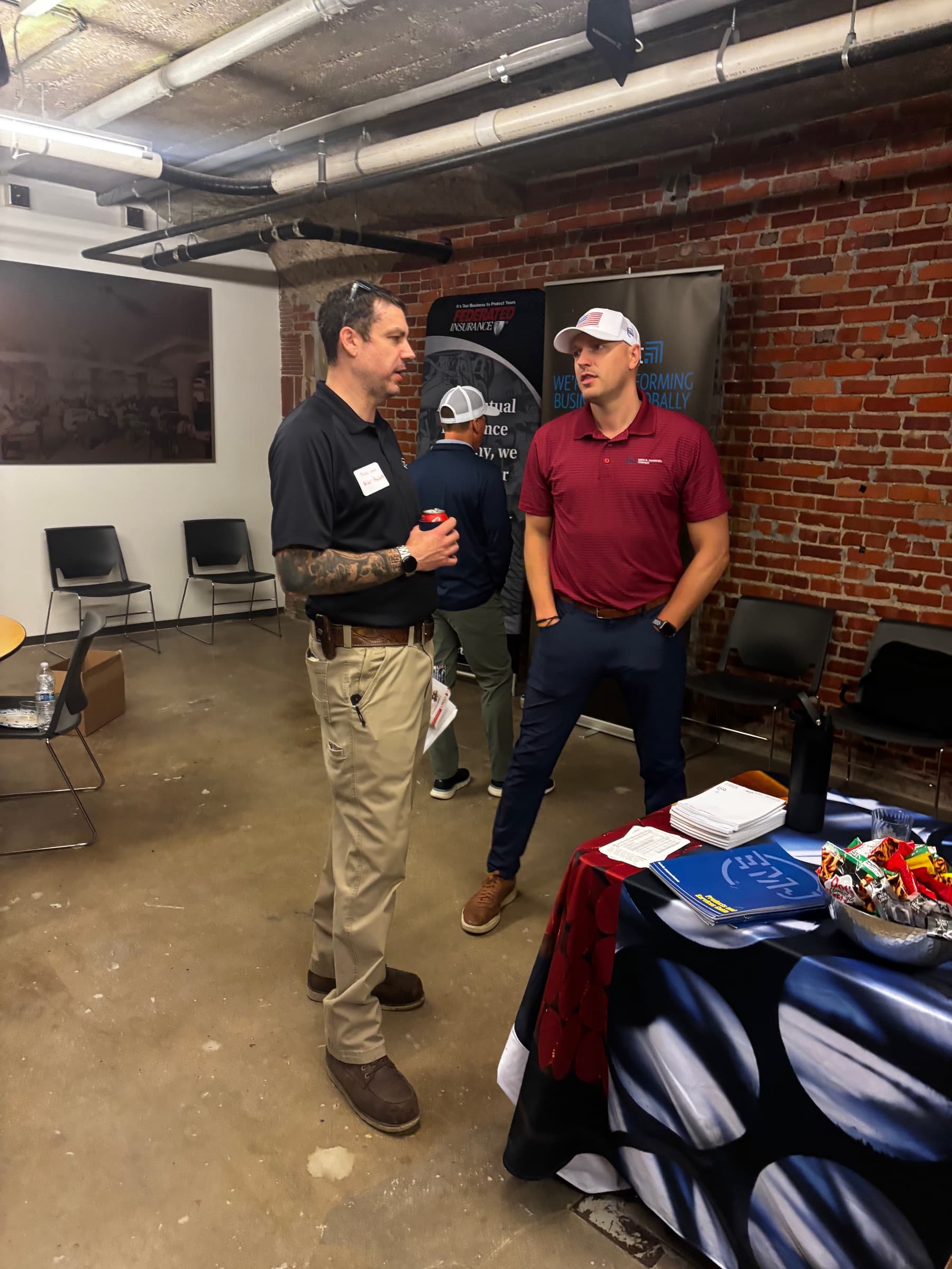 Two men in conversation beside a vendor banner at a networking event