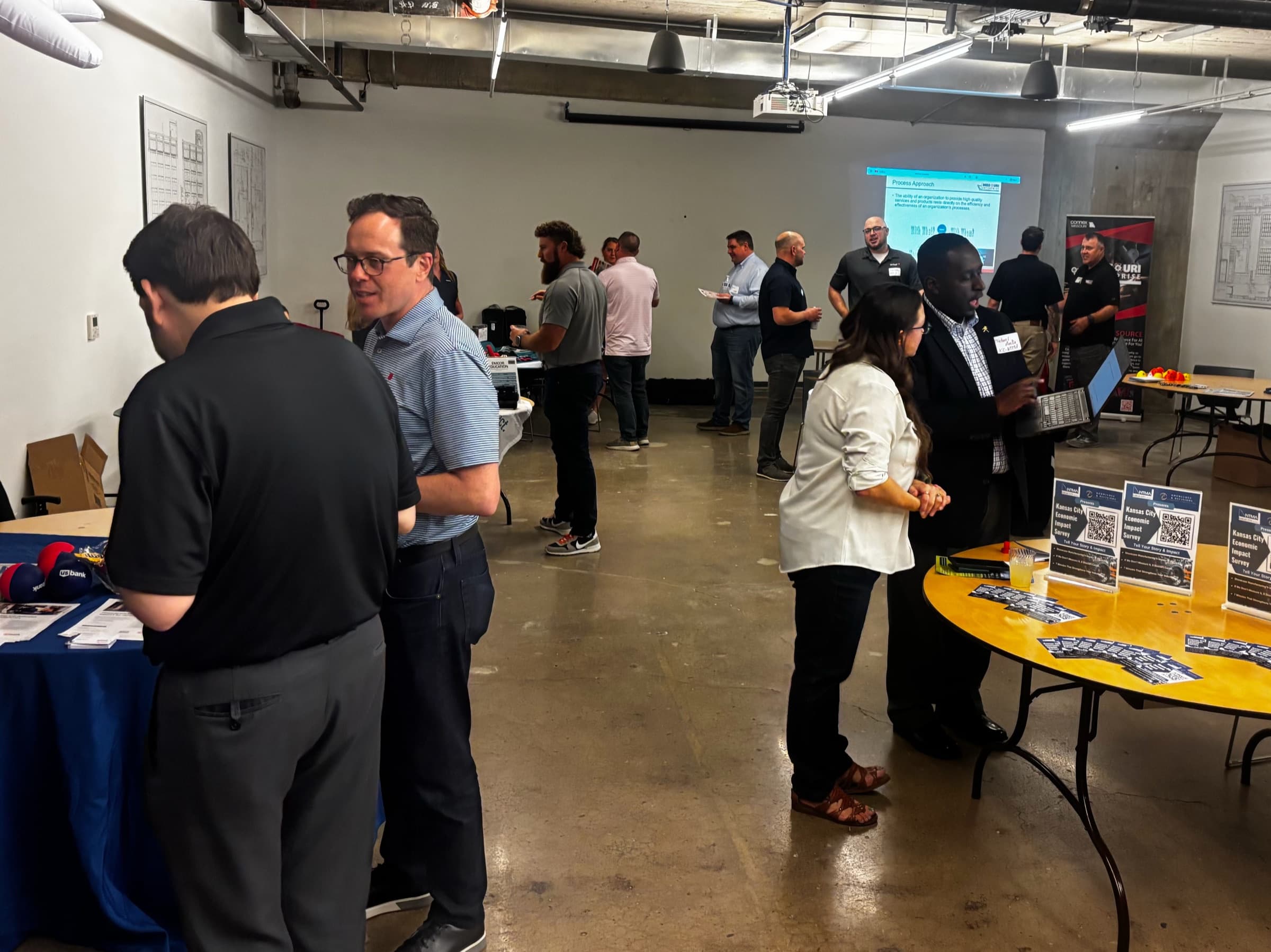 Members talking in small groups at a vendor showcase in an industrial event space