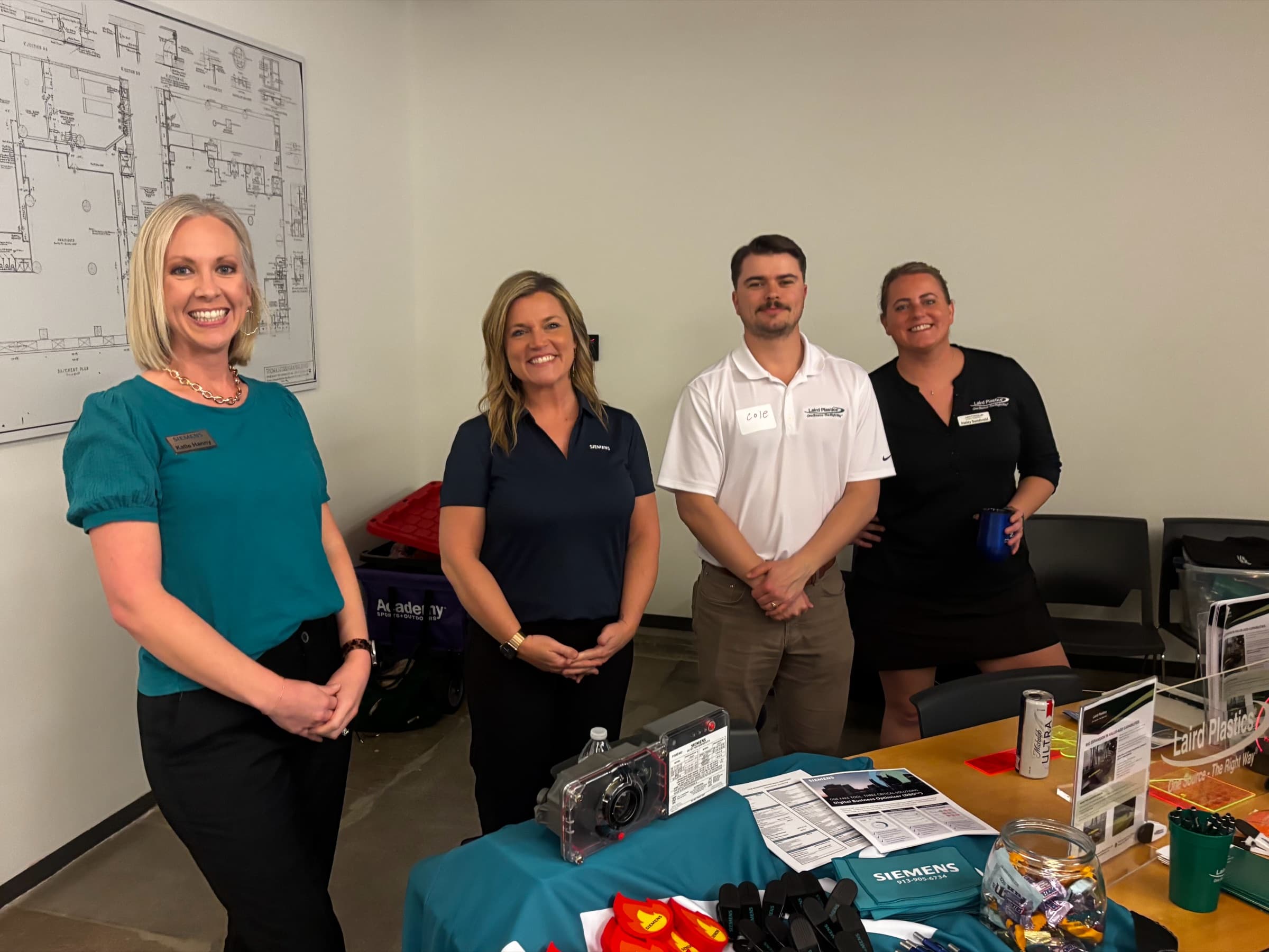 Four associate members behind a vendor table of samples and giveaways