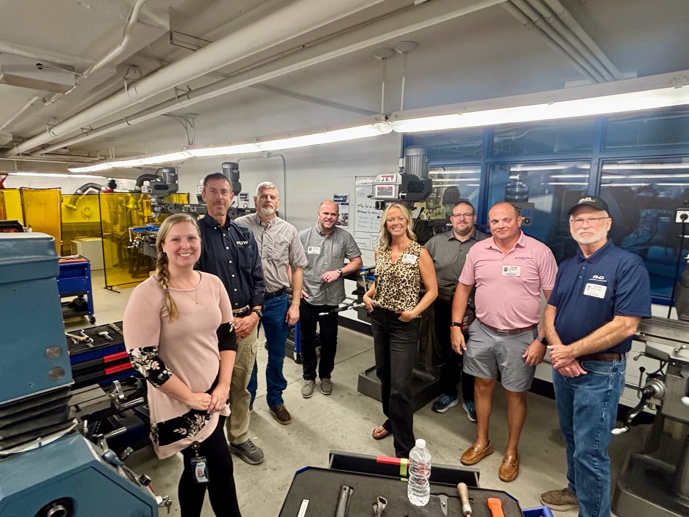 Eight chapter members and teachers standing among the machines in a school shop